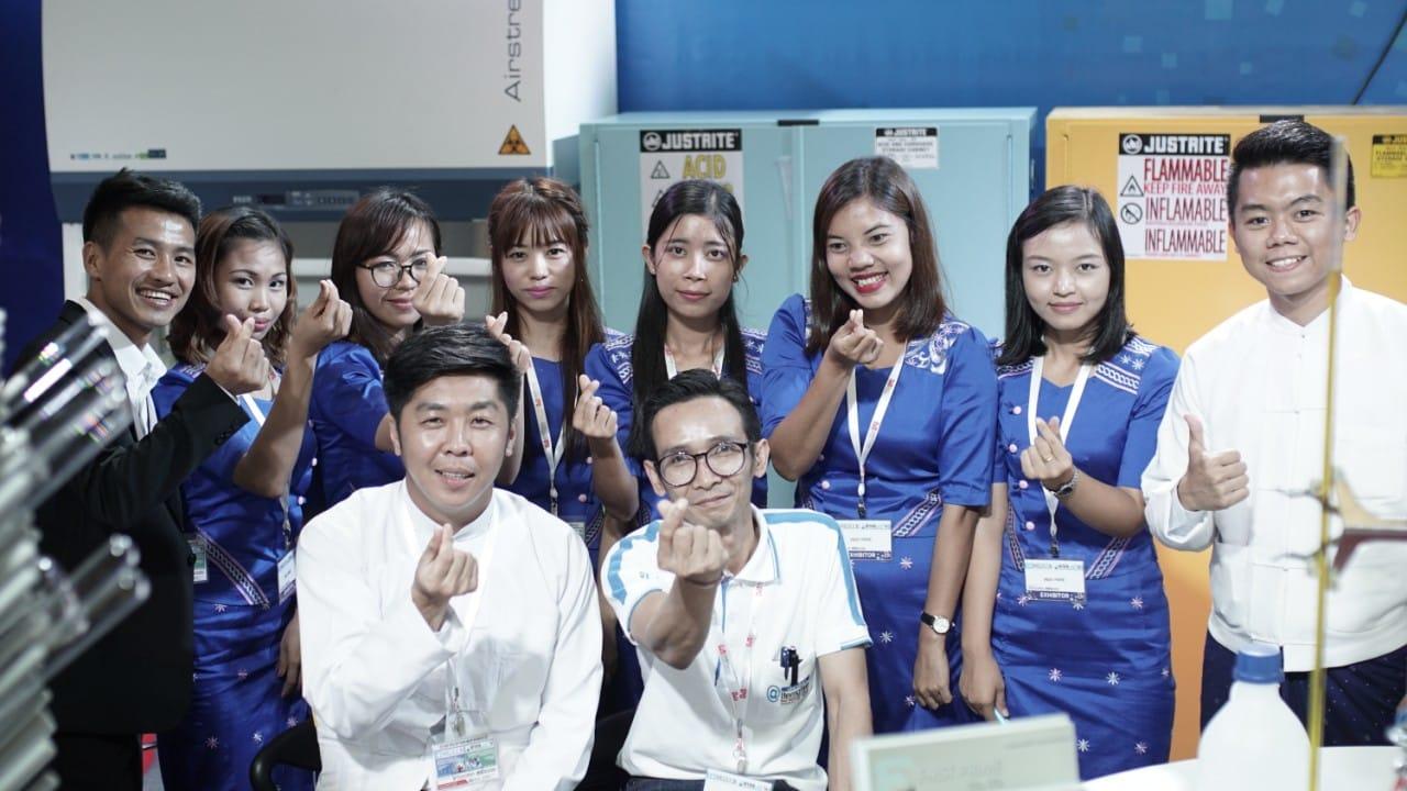 FIRST PRIME team making a finger-heart gesture at the booth