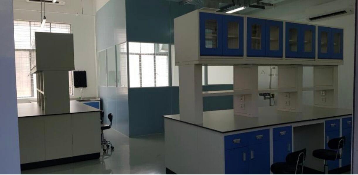 The Molecular Lab after renovation — island bench with blue cabinets and reagent racks, epoxy floor, and a partitioned side room